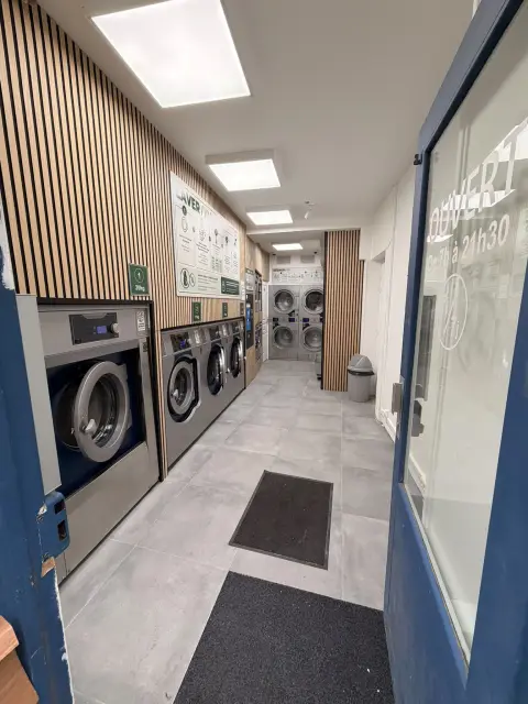 Lave-linge et séchoirs dans la salle de la Laverie Belleville, lambris de chêne